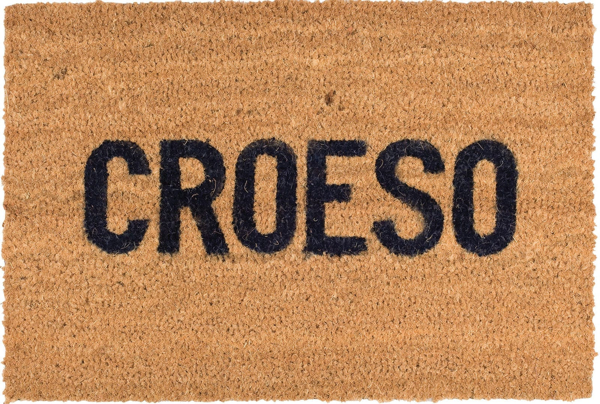 Image depicts a natural brown coir mat with 'Croeso' written in a black appealing font on it.