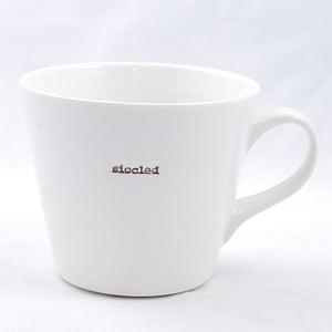 White simple bucket mugs with colourful lettering  in typewriter style font which read 'Dad','Bodlon','Mam,'Eisteddfod','Hapus','Taid','Siocled'.
